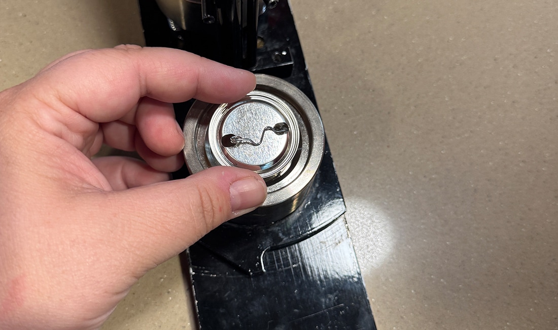 Step 6 of Button Making 101 is to place the pin back, squiggly side up, in the deep end of the button machine