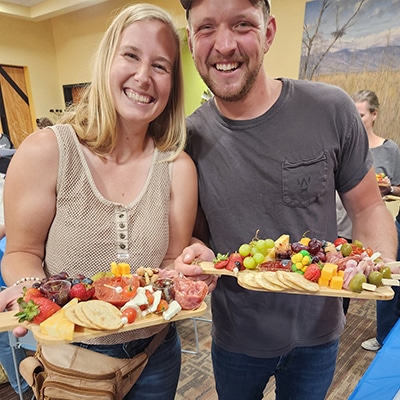 Two patrons show off the charcuterie boards they created at the Hudson Public Library