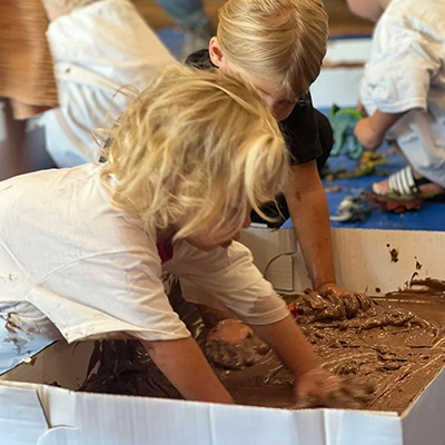 Kids play in sand during the Let's Get Messy playtime at Hudson Public Library